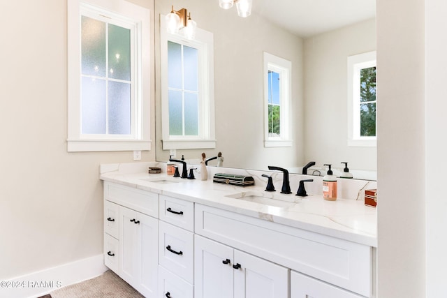 full bathroom with double vanity, baseboards, and a sink