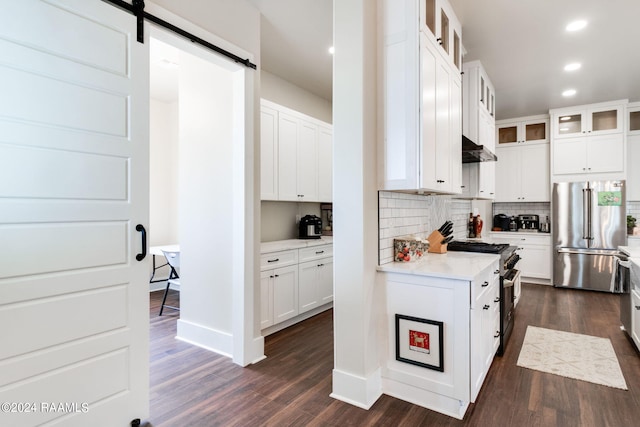 kitchen with dark wood-type flooring, high quality appliances, a barn door, decorative backsplash, and white cabinets