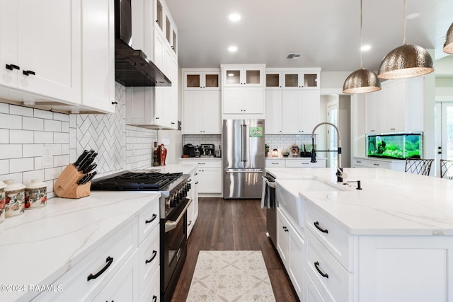 kitchen with pendant lighting, white cabinetry, high quality appliances, extractor fan, and an island with sink