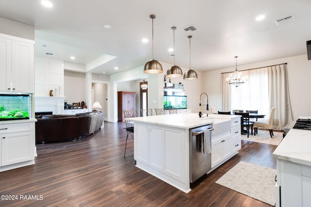 kitchen featuring hanging light fixtures, light stone counters, an island with sink, white cabinets, and stainless steel dishwasher