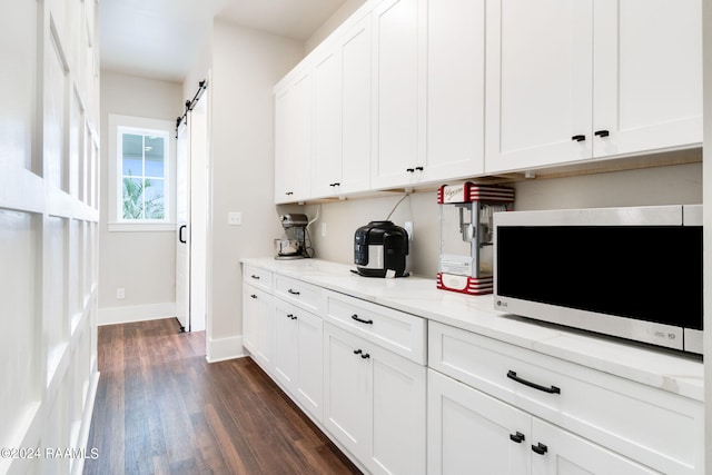 kitchen with baseboards, white cabinetry, a barn door, and dark wood-style flooring