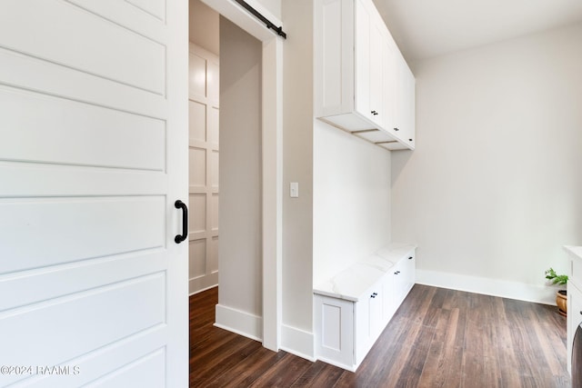 mudroom featuring a barn door, dark wood-style floors, and baseboards