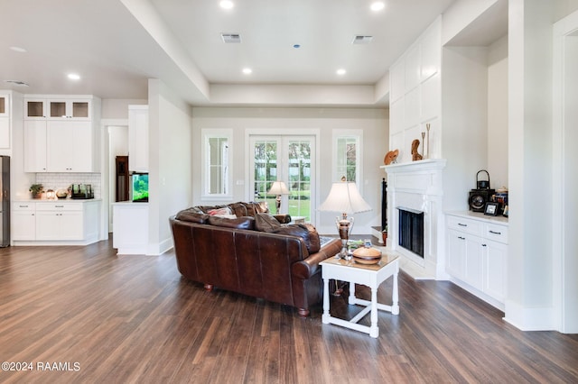 living room with dark wood finished floors, visible vents, a fireplace with raised hearth, and recessed lighting