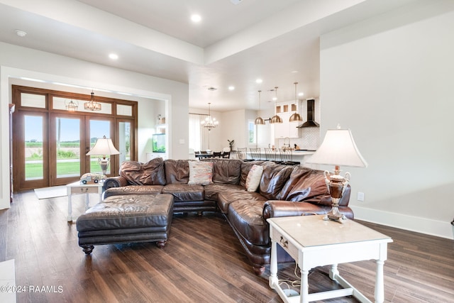 living room with a notable chandelier, baseboards, dark wood-type flooring, and a healthy amount of sunlight