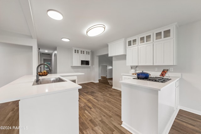 kitchen featuring white cabinetry, sink, kitchen peninsula, dark hardwood / wood-style flooring, and black gas stovetop