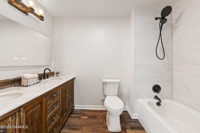 full bathroom with vanity, hardwood / wood-style flooring, tiled shower / bath, and toilet