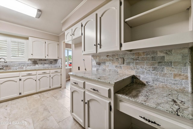 kitchen with white cabinetry, sink, decorative backsplash, ornamental molding, and light stone countertops