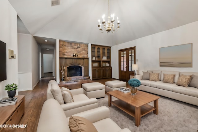 living room with hardwood / wood-style flooring, a brick fireplace, high vaulted ceiling, and french doors