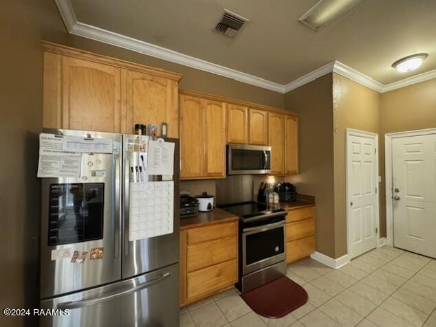 kitchen featuring light tile patterned floors, crown molding, and stainless steel appliances