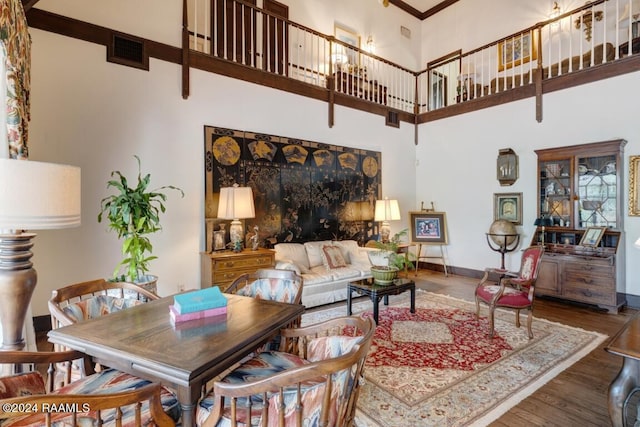 living room with crown molding, hardwood / wood-style floors, and a high ceiling