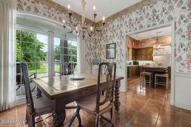 dining space with an inviting chandelier, ornamental molding, and tile patterned flooring