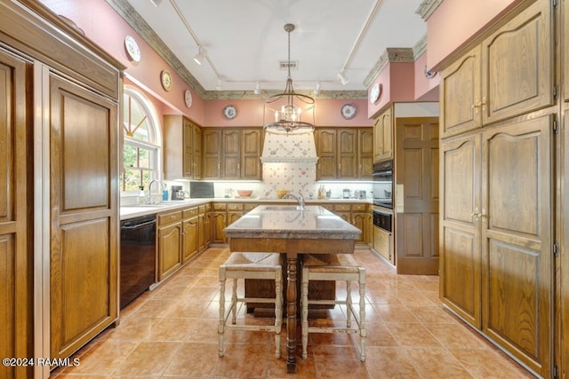 kitchen featuring sink, a kitchen island with sink, a kitchen breakfast bar, black dishwasher, and tasteful backsplash