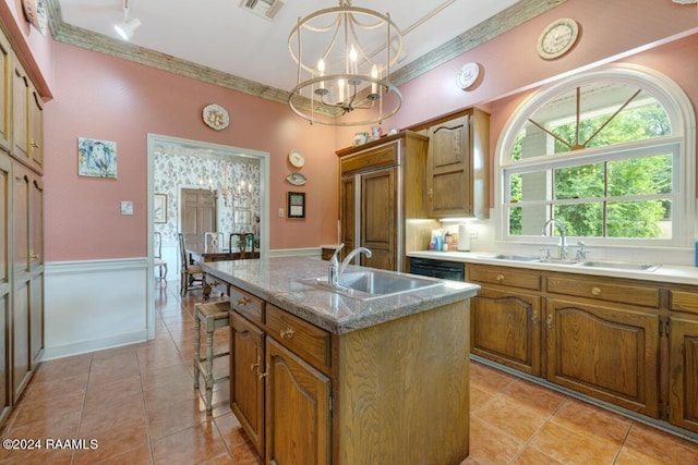 kitchen with pendant lighting, light tile patterned floors, sink, a kitchen island with sink, and a notable chandelier