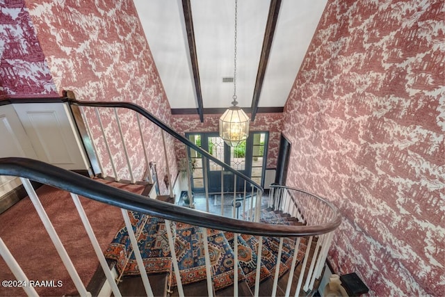 staircase with an inviting chandelier and high vaulted ceiling