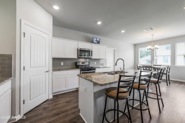 kitchen featuring white cabinetry, an island with sink, sink, dark stone counters, and appliances with stainless steel finishes