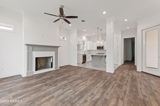 unfurnished living room with wood-type flooring, sink, and crown molding