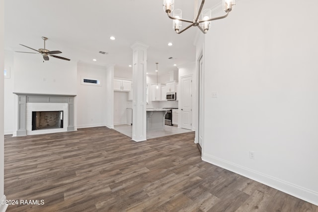 unfurnished living room featuring dark hardwood / wood-style flooring and ceiling fan with notable chandelier