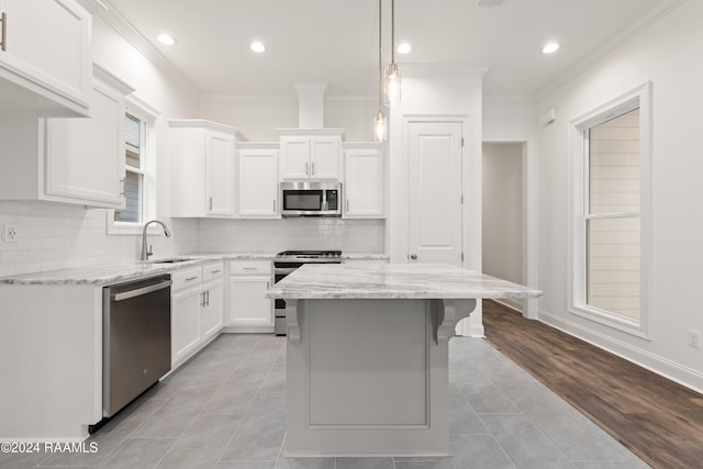 kitchen with light stone countertops, stainless steel appliances, sink, and white cabinets