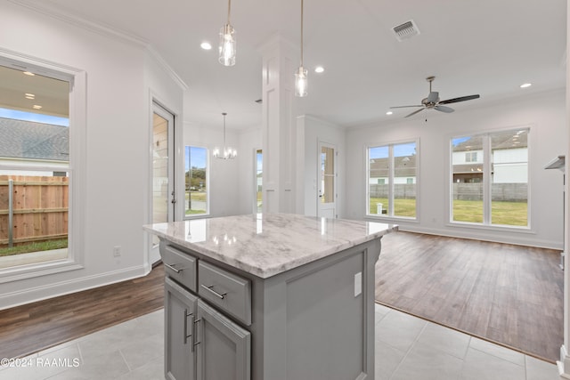 kitchen featuring pendant lighting, gray cabinetry, a center island, and light tile patterned floors