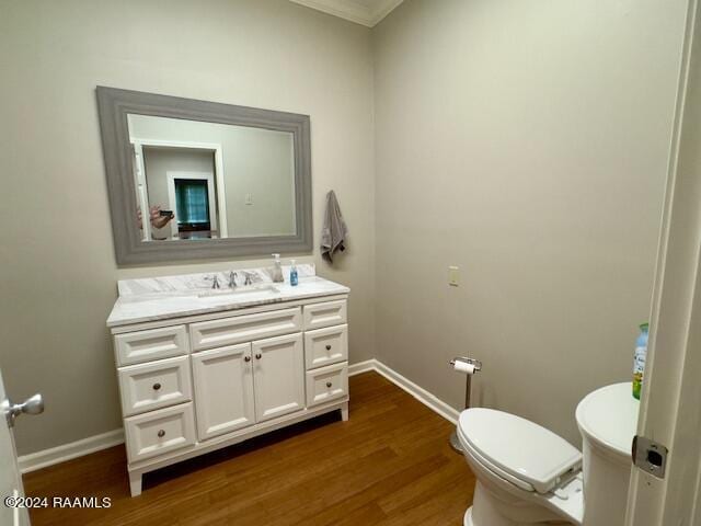 bathroom with wood-type flooring, vanity, crown molding, and toilet