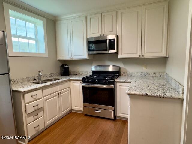 kitchen featuring appliances with stainless steel finishes, sink, white cabinets, and light wood-type flooring