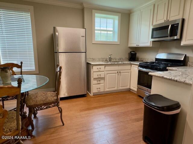 kitchen with white cabinetry, sink, light stone counters, stainless steel appliances, and light wood-type flooring