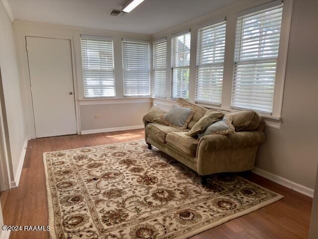 living area with crown molding and hardwood / wood-style flooring