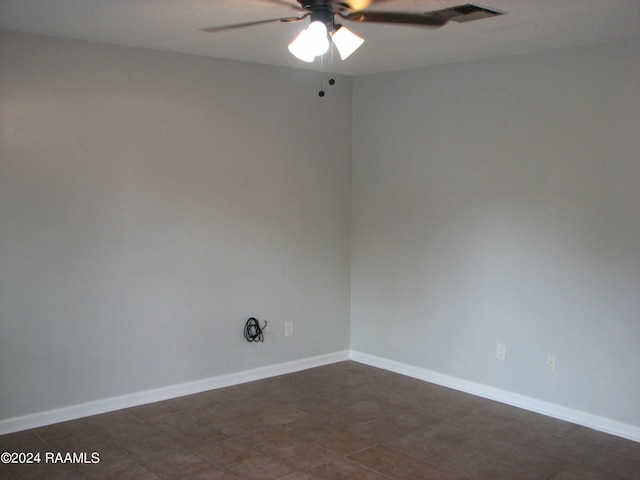 empty room with ceiling fan and dark tile patterned flooring