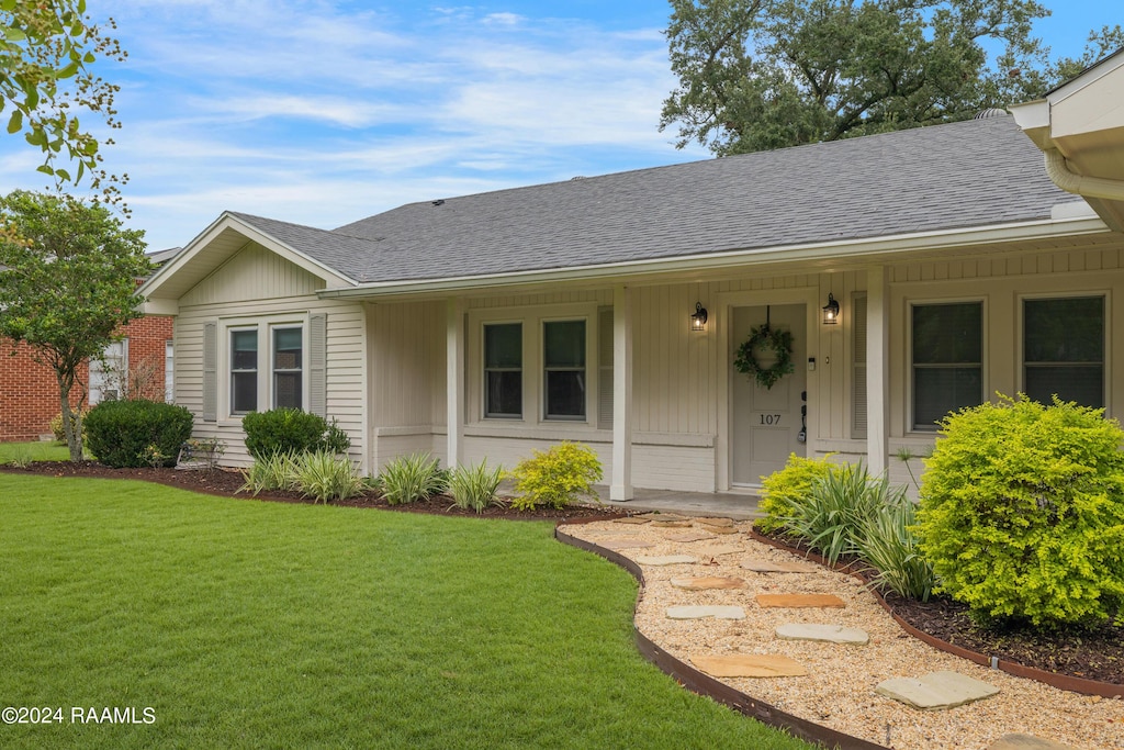 view of front of property featuring covered porch, a shingled roof, and a front yard