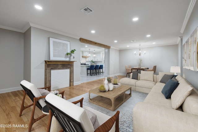 living room featuring light hardwood / wood-style flooring, crown molding, and a notable chandelier