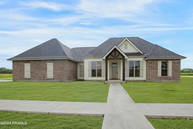 view of front facade featuring brick siding, roof with shingles, and a front lawn