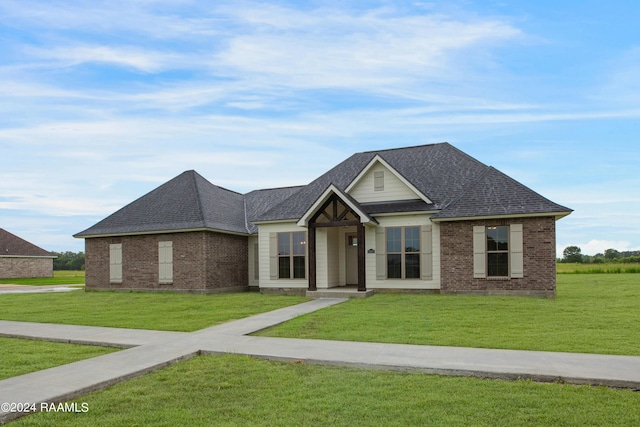 view of front of home with brick siding, a front yard, and a shingled roof