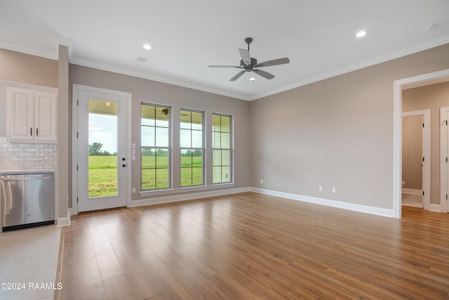 spare room with a healthy amount of sunlight, crown molding, and light wood finished floors