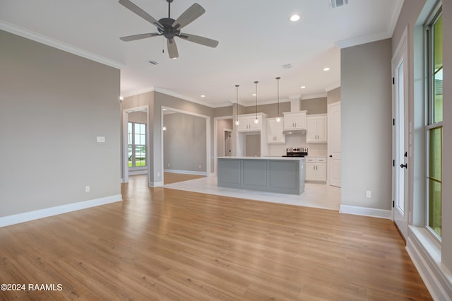 unfurnished living room with visible vents, baseboards, light wood-style flooring, and crown molding