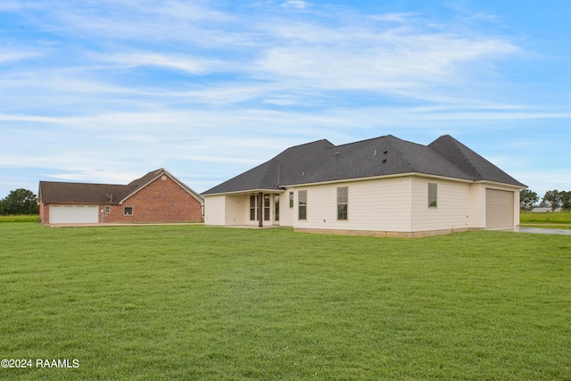 back of house with a yard, a garage, and roof with shingles