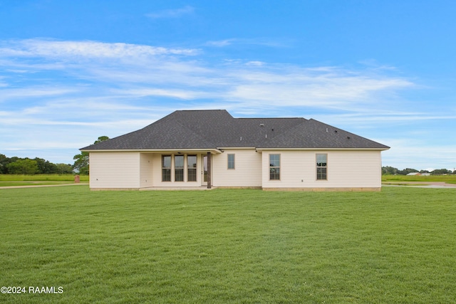 rear view of house with a shingled roof and a yard