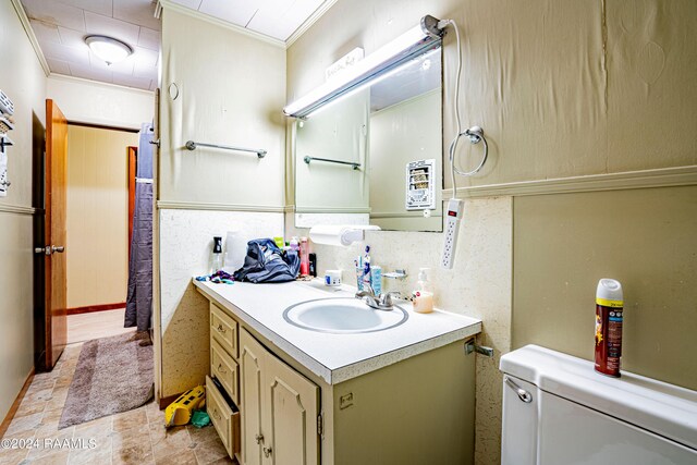 bathroom featuring tile patterned flooring, crown molding, vanity, and toilet