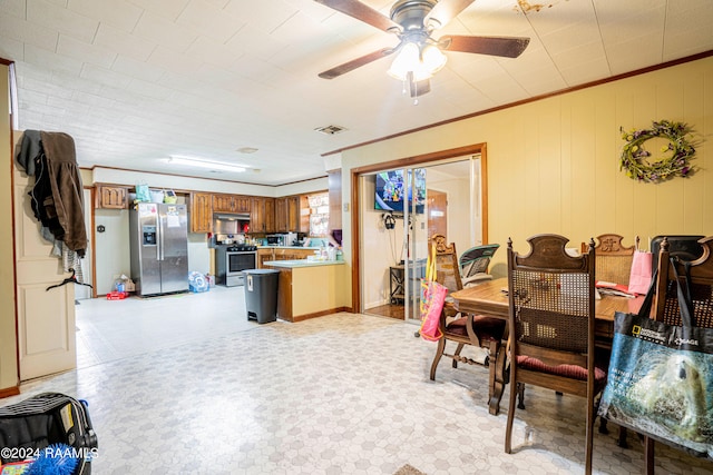 tiled dining space with ceiling fan and ornamental molding