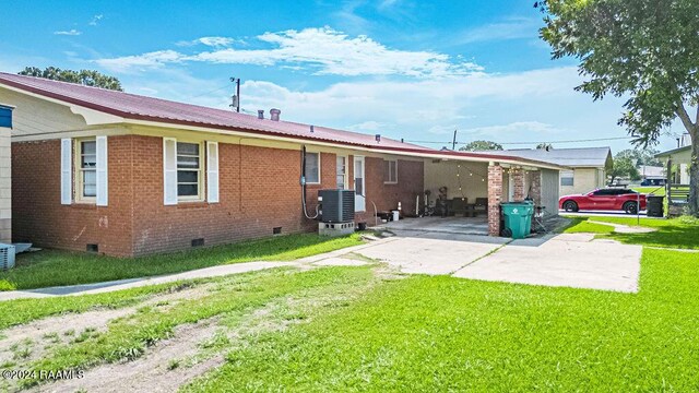 rear view of property featuring central AC unit and a lawn