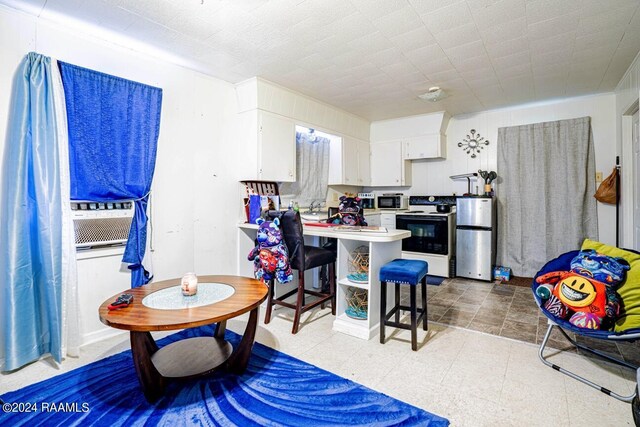 interior space with stainless steel refrigerator, white cabinetry, light tile patterned flooring, and range with electric stovetop