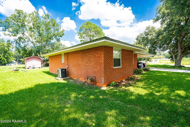 view of home's exterior with cooling unit, a carport, and a lawn