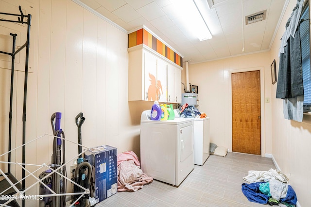 clothes washing area with cabinets, crown molding, and washing machine and clothes dryer