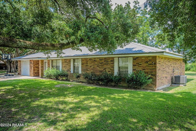 ranch-style house with a garage, cooling unit, and a front yard