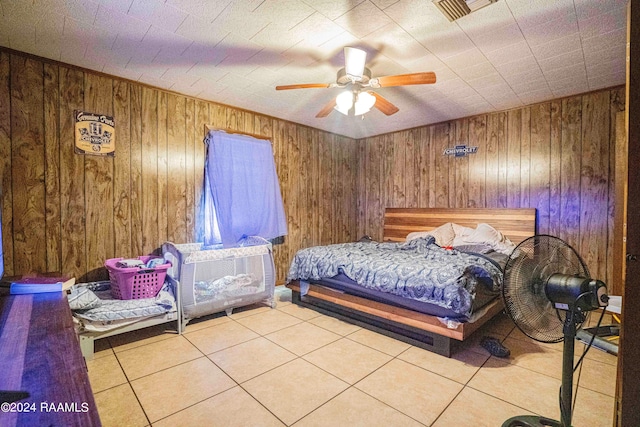 tiled bedroom featuring ceiling fan and wood walls