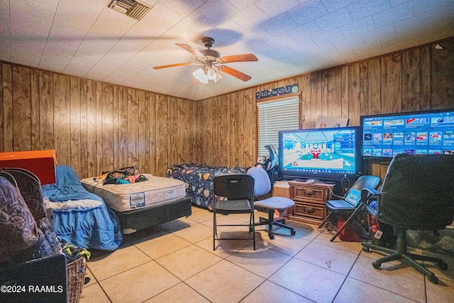 bedroom featuring wooden walls, ceiling fan, and light tile patterned flooring