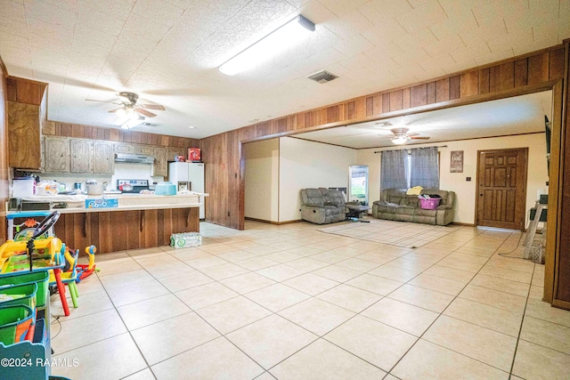 kitchen featuring ceiling fan, white refrigerator with ice dispenser, wooden walls, and kitchen peninsula