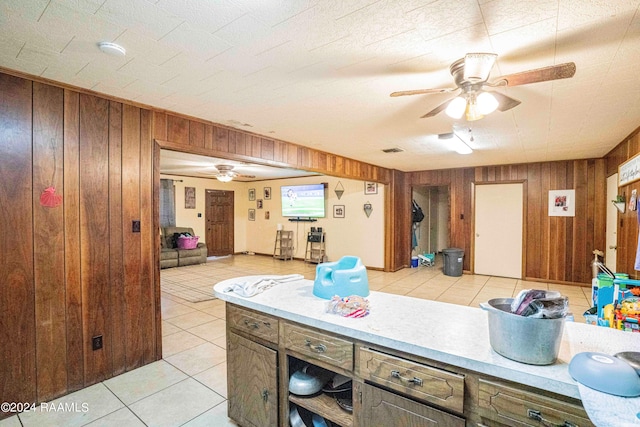 kitchen featuring light tile patterned flooring, ceiling fan, and wood walls