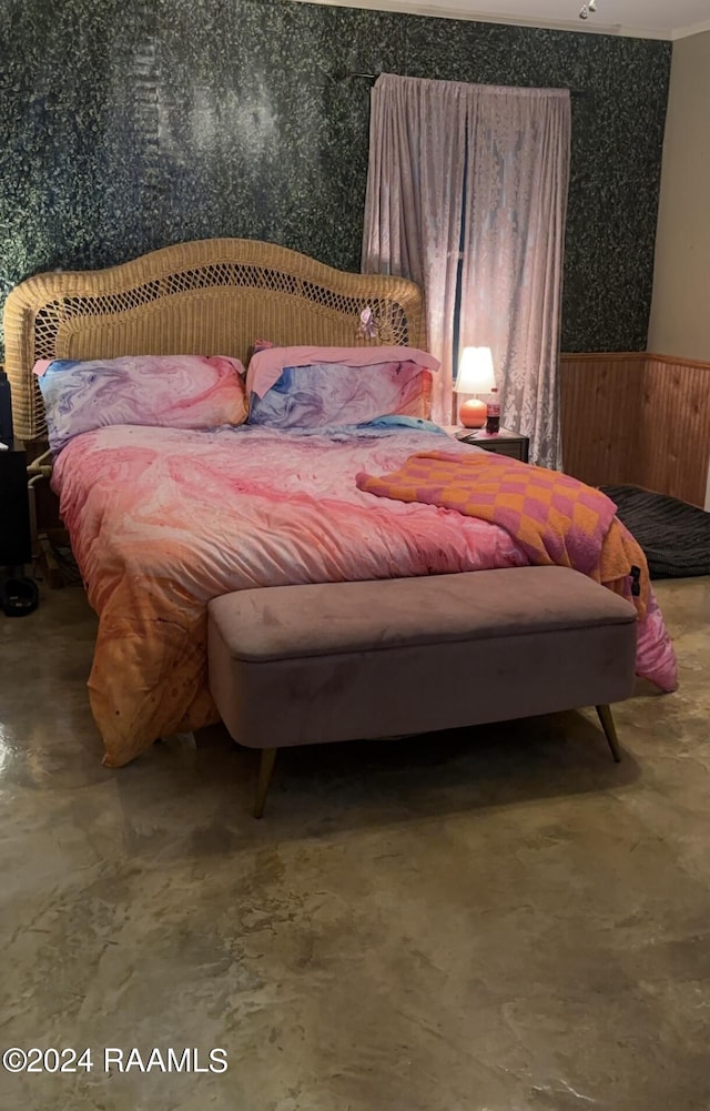 bedroom featuring concrete floors and wainscoting