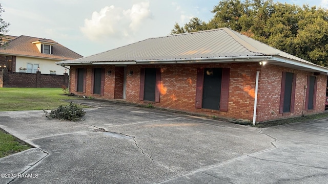 rear view of house featuring metal roof, brick siding, a yard, and fence