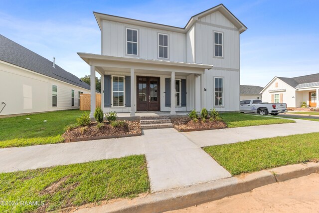 modern inspired farmhouse featuring a front yard and covered porch